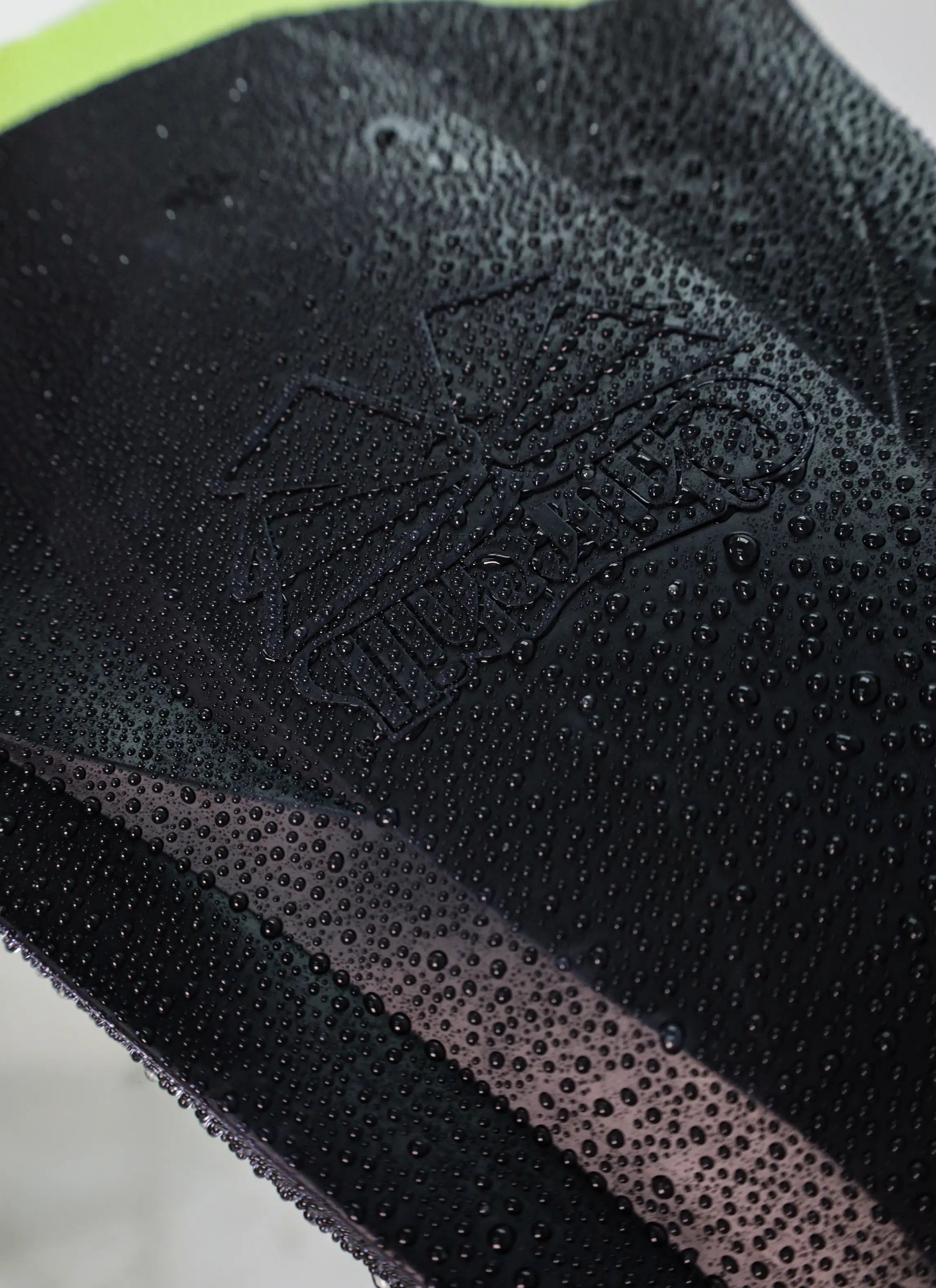 Close-up of a wet black bodyboard surface with embossed texture and water droplets