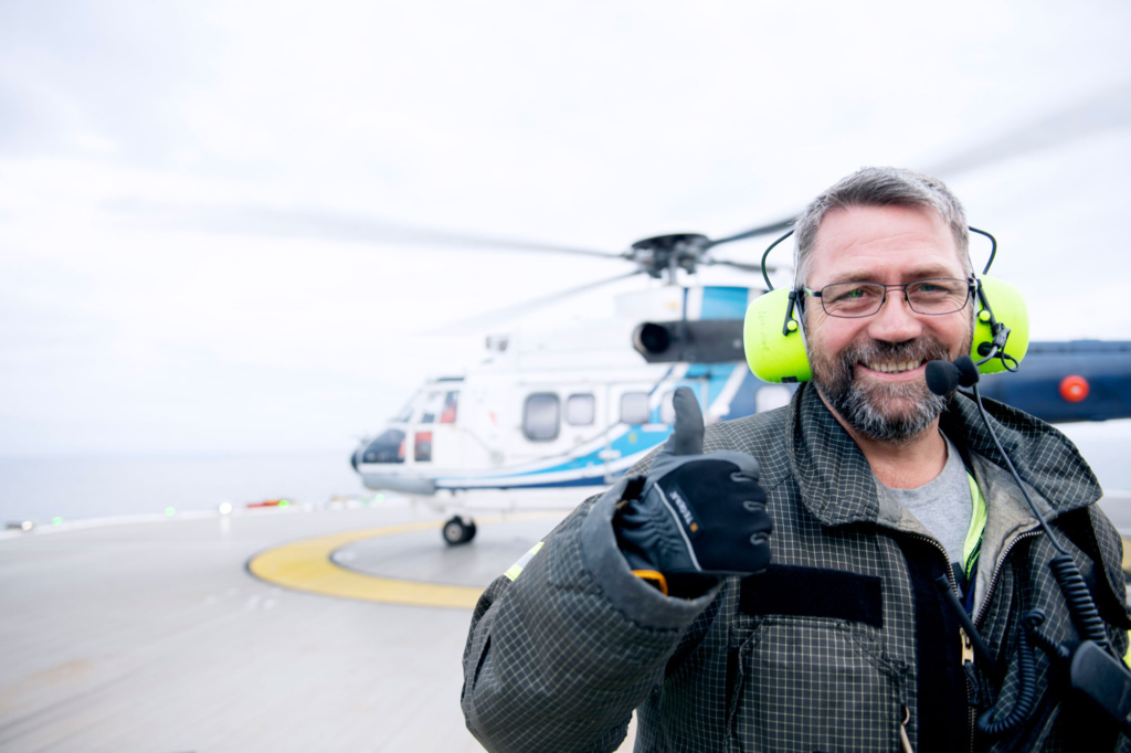 Mann står foran et helikopter. Foto