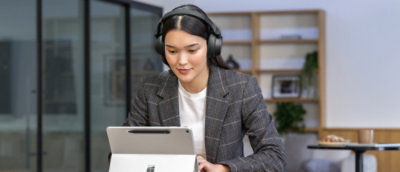 Seseorang memakai headphone dan menatap tablet.