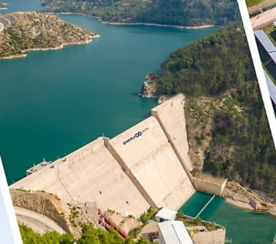 Ein großer Betonstaudamm mit Wasser und einer grünen Insel im Hintergrund.
