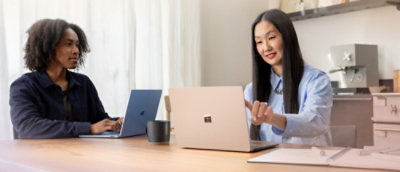 A man and woman sitting at a table with laptops.