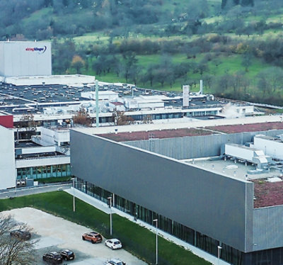 صورة لمنزل ريفي ساحر بحديقة مُعتنى بها جيداً، تضم كرسيين على العشب وأزهاراً نابضة بالحياة 