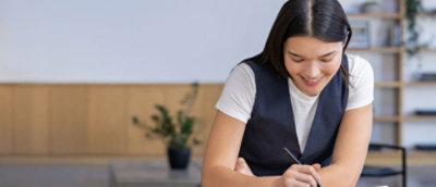 Una mujer escribiendo algo con lápiz.