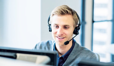 Person mit Headset vor Computerbildschirmen.