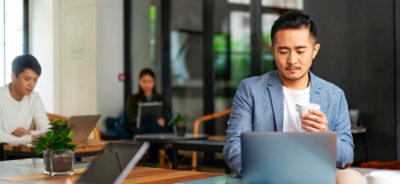 Человек сидит за столом с ноутбуком.