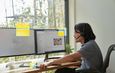Person using a desktop computer with dual monitors and a headset.