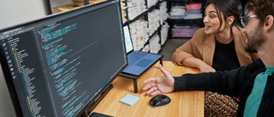 A man and woman are smiling together while looking at a laptop.