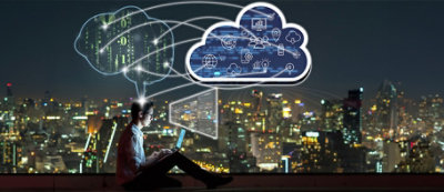 A person sitting with a laptop at night, with a digital cloud above them filled with icons representing various technologies, overlays a cityscape
