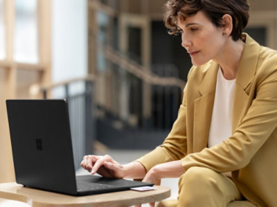 Een persoon die aan een tafel zit met een laptop.