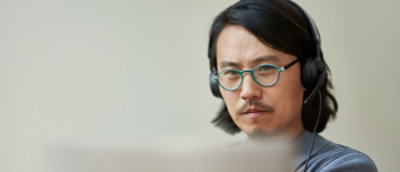 Gözlük takan ve dizüstü bilgisayarda çalışan bir adam.