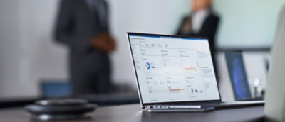 A laptop on a table with a screen displaying content and a blurry background.