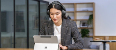 Een vrouw die naar een laptop kijkt die een hoofdtelefoon draagt