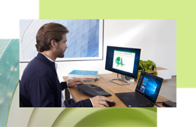 Homme travaillant sur un ordinateur de bureau et un ordinateur portable à un bureau moderne, analysant des données sur un écran avec des graphiques.