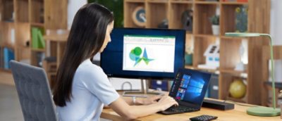 Een vrouw die aan een bureau zit en een computer gebruikt.