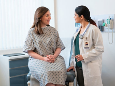 A doctor wearing stethoscope talking to a patient.