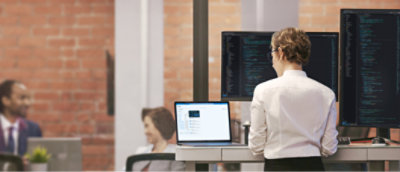 Two people are discussing something on a screen, with one holding a tablet displaying information.