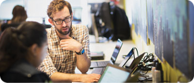 En mann med briller ser på en bærbar datamaskin.