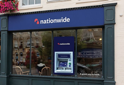 Un primer plano de un cajero automático de un banco con una señal azul que muestra texto blanco que incluye Nationwide y Una buena forma de ir al banco.
