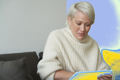 Person seated on a sofa using a tablet in a minimalist indoor setting