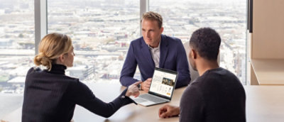 A group of people sitting together at a table with laptop.