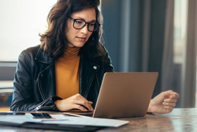 A person wearing glasses looking at a laptop.
