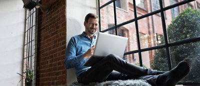 Personne assise sur un tapis de fourrure et utilisant un ordinateur
