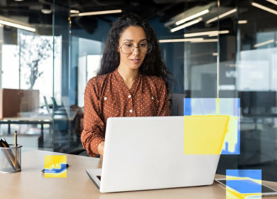 Woman in orange sweater using laptop displaying a website about data security on its screen at a wooden table