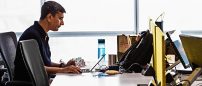 Мужчина сидит за столом и смотрит на ноутбук.