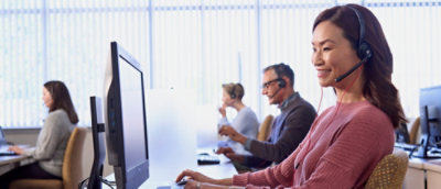 Um grupo de pessoas trabalhando em mesas com computadores e fones de ouvido.