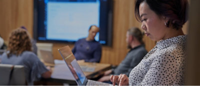 Closeup of a woman working on the laptop and some people behind her