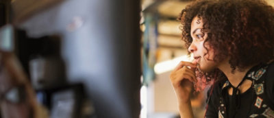 最新のオフィス環境でコンピューターで熱心に作業している、カーリー ヘアの若い女性。