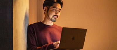 Ein Mann in einem roten Hemd verwendet einen Laptop.