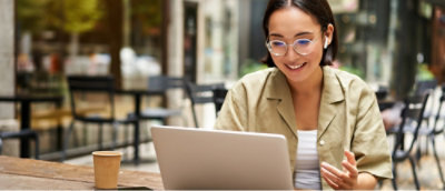 Seorang wanita berkacamata bekerja, menggunakan laptop.