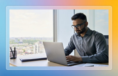 Personne travaillant sur un ordinateur portable à un bureau près d’une fenêtre.