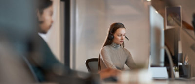 Personne portant un casque, travaillant à un bureau avec des écrans d’ordinateur.