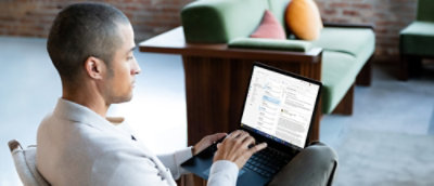 Personne utilisant un ordinateur portable assis sur un canapé dans un espace de travail moderne.