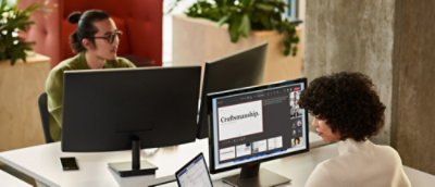 Une équipe travaillant sur des ordinateurs de bureau tout en passant en revue des conceptions et du contenu sur plusieurs écrans dans un bureau.