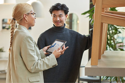 Femme tenant une tablette à la main tout en parlant avec un homme