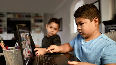 Két laptopot használó gyerek a nappaliban