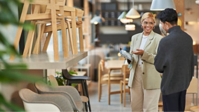 A woman holds a tablet in her hand while talking to a man