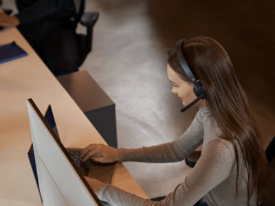一名戴著耳麥在膝上型電腦上工作的女人。