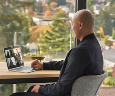 صورة لشخص يجلس على مكتب ويشارك في مؤتمر فيديو على جهاز كمبيوتر محمول.