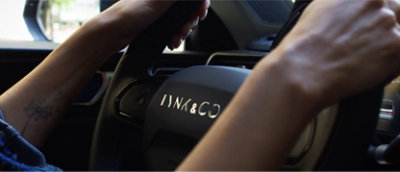 여성의 손이 자동차 운전대 위에 있습니다.