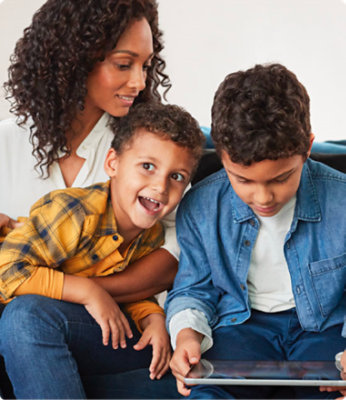 Una madre con dos hijos en un sofá jugando.