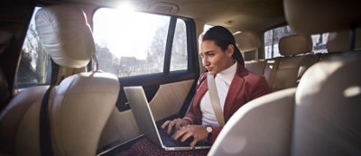 Una mujer sentada en un coche con un portátil.