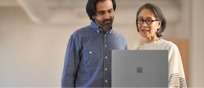 Two colleagues collaborating over a laptop in an office environment.
