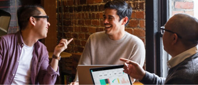 Gruppo di persone sedute intorno a un tavolo con portatili.