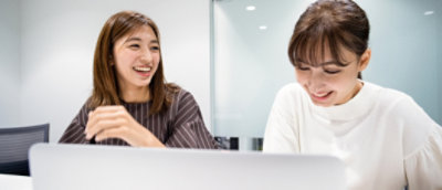 Et par kvinder, der kigger på en computer og smiler