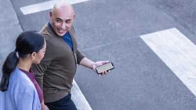 屋外で歩きながらスマートフォン上の情報を確認している 2 人。