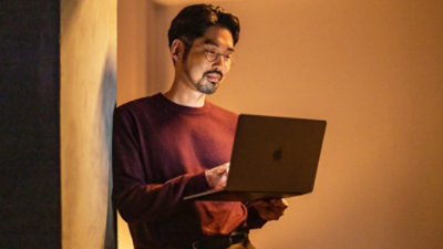 person using laptop against warm light background.